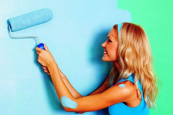 девушка красит валиком стену